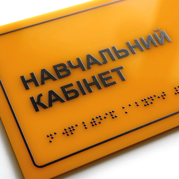 Крупний план тактильної таблички «Навчальний кабінет» зі шрифтом Брайля та рельєфним текстом на жовтому акрилі