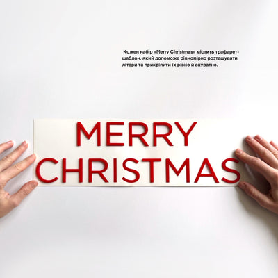 A pair of hands holding a sign with the text "MERRY CHRISTMAS" written on it.
