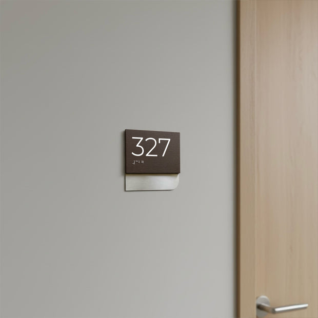 a brown sign with the number 327 displayed on it, mounted on a wall next to a wooden door.