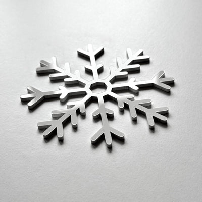 A silver snowflake-shaped object is centered on a plain white background.