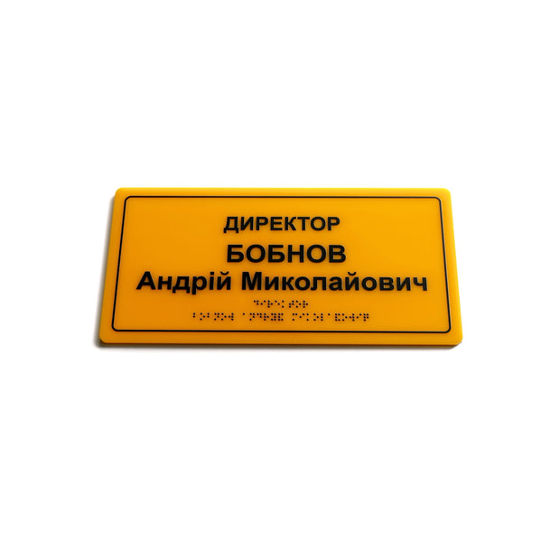 Іменна табличка «Директор» зі шрифтом Брайля, жовтий акрил і контрастний чорний напис, вид під нахилом