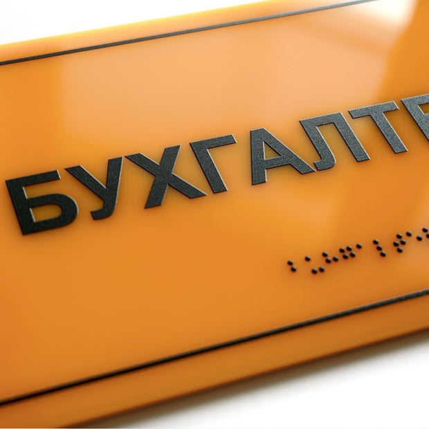 Крупний план тактильної таблички «Бухгалтерія» зі шрифтом Брайля, жовтий акрил і рельєфні чорні літери