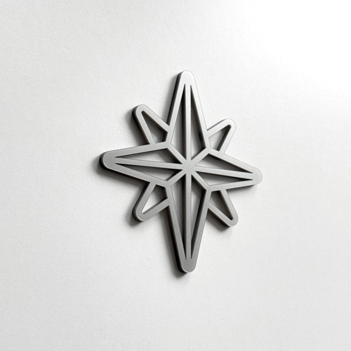 A silver star-shaped object is mounted on a white wall.
