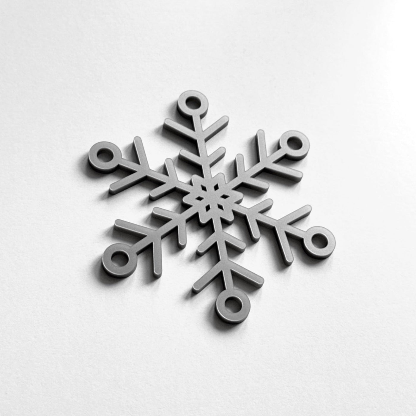 A silver snowflake ornament is displayed against a white background.