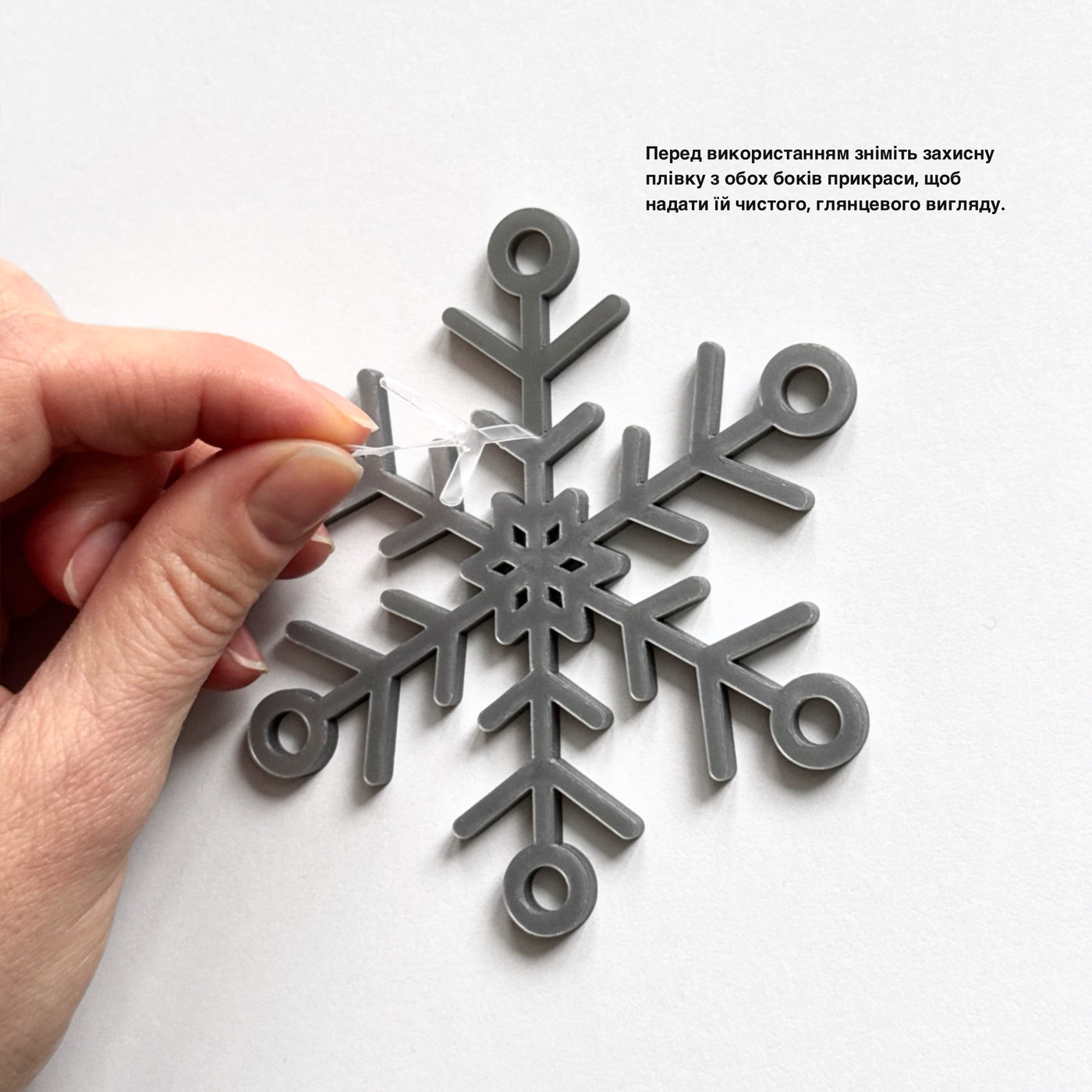 A hand is sticking a clear plastic piece into a gray snowflake-shaped object.